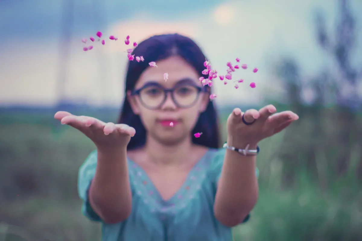 Mujer joven jugando con pétalos al aire libre