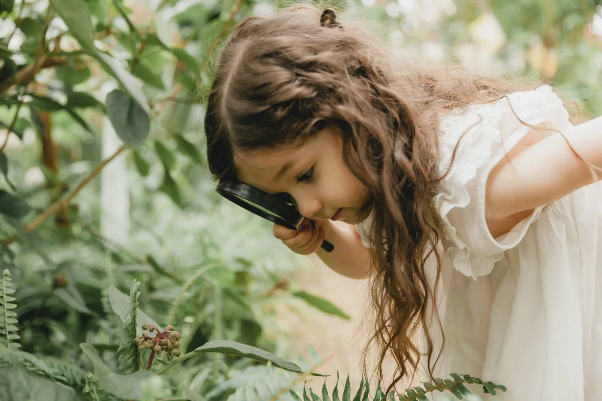 Niña explorando la naturaleza con una lupa