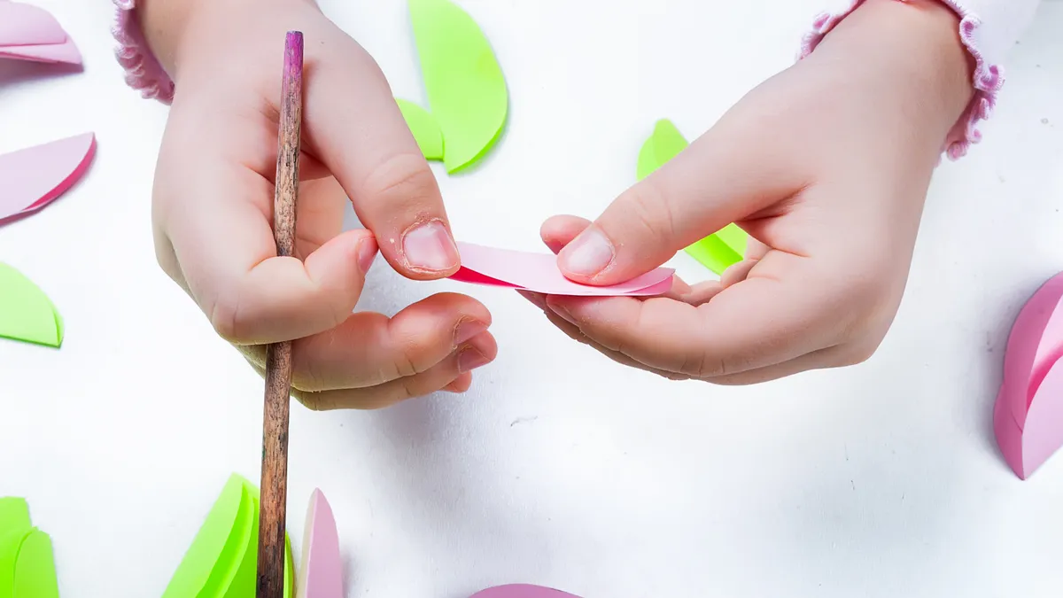Niño haciendo manualidades con papel y colores sobre la mesa