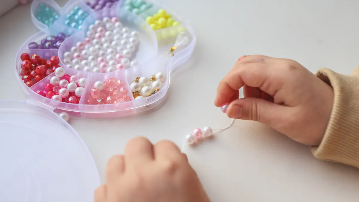 Manos de un niño ensartando cuentas, ejercitando la motricidad fina