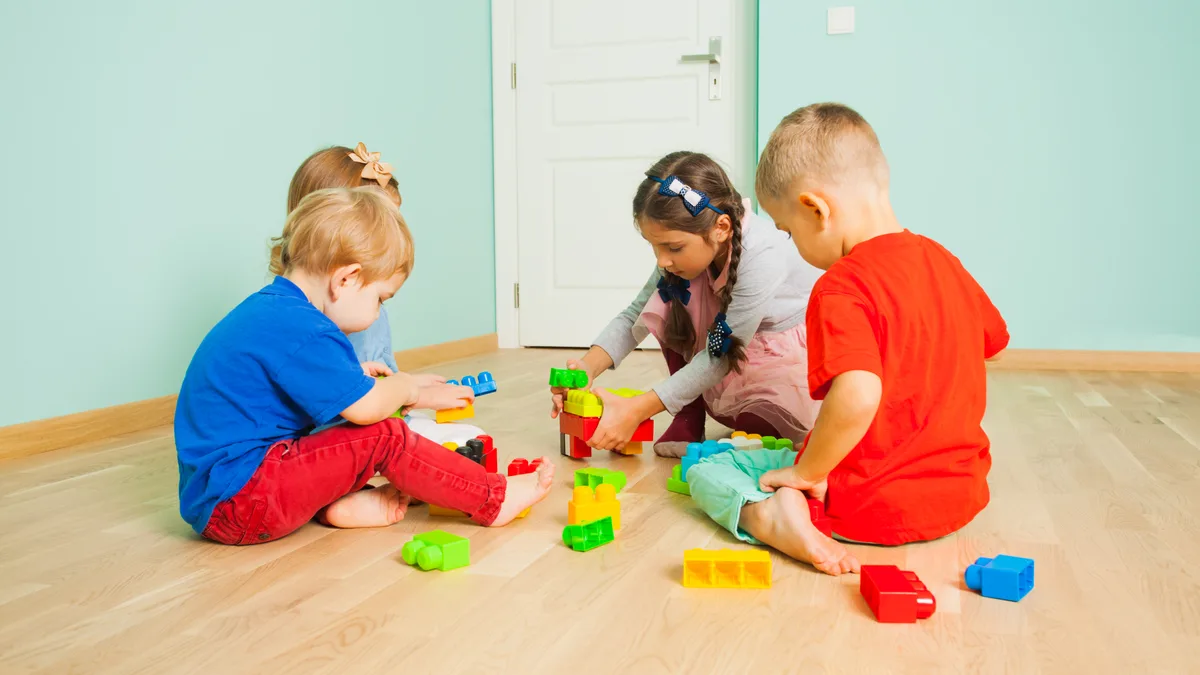 Niños pequeños jugando juntos con bloques de construcción de colores en el suelo