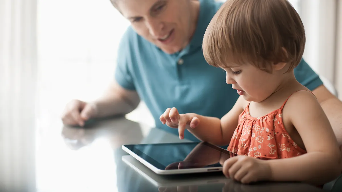 Madre acompañando a su hijo mientras usa una tablet educativa