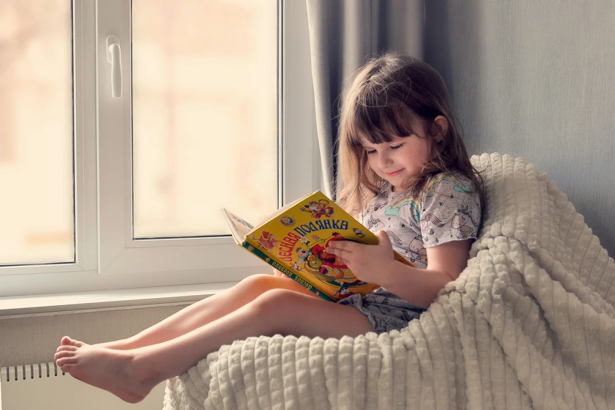Niña concentrada explorando un libro con audio interactivo en casa