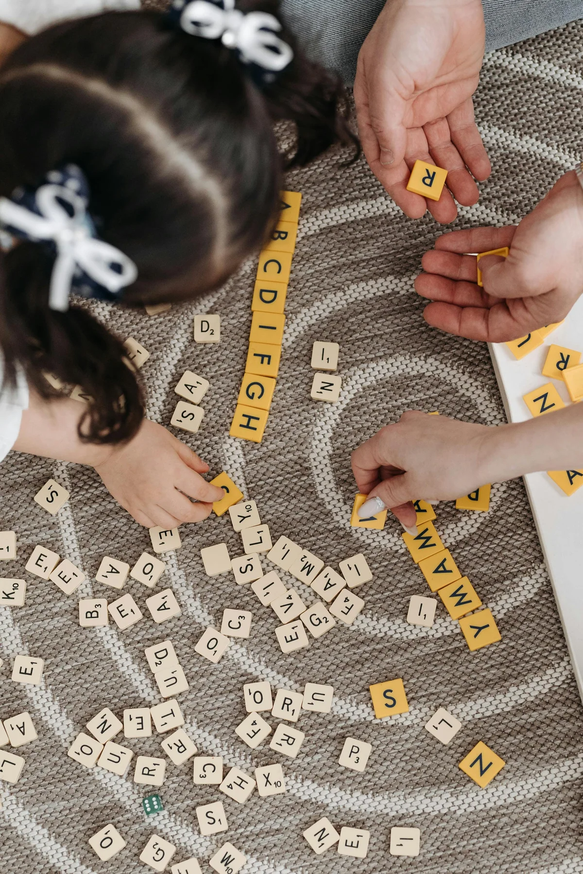Familia jugando juntos y construyendo la palabra FAMILY en Scrabble
